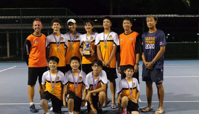 A tennis team and coaches gathered together on an outdoor court
